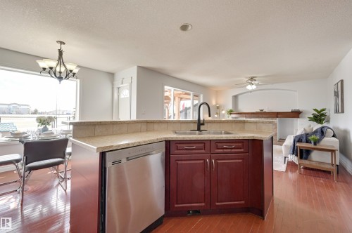 The kitchen features a stainless steel dishwasher, a sink with a dark-toned faucet, and a countertop with a tiled backsplash - 24 Birchmont Drive, Leduc, AB - Indoor Photo Showing Kitchen With Double Sink