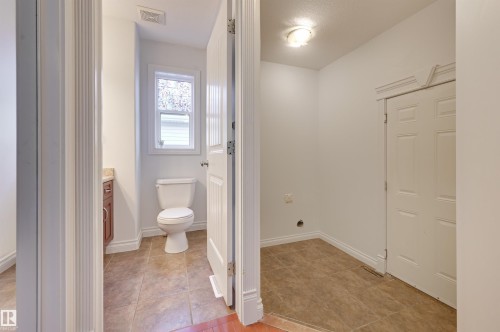 This functional space features a white toilet, a window with decorative privacy film, and a vanity with a countertop and cabinet - 24 Birchmont Drive, Leduc, AB - Indoor