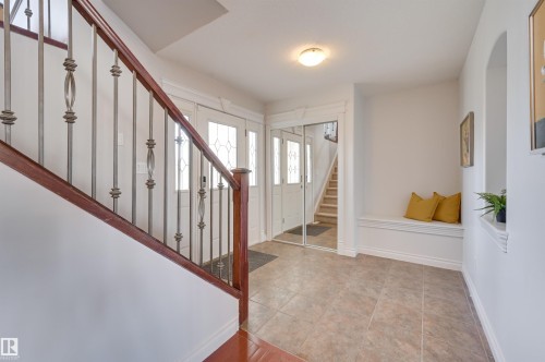 The entryway features tiled flooring, a built-in bench, and a staircase with a wooden handrail and wrought iron balusters - 24 Birchmont Drive, Leduc, AB - Indoor Photo Showing Other Room