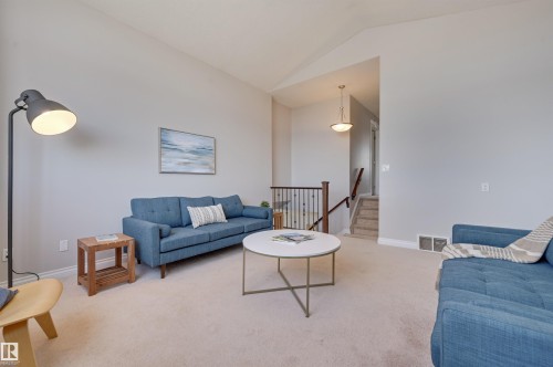 The inviting living area features light-colored carpeting and vaulted ceilings, creating an airy atmosphere - 24 Birchmont Drive, Leduc, AB - Indoor Photo Showing Living Room