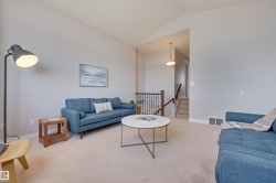 The inviting living area features light-colored carpeting and vaulted ceilings, creating an airy atmosphere - 