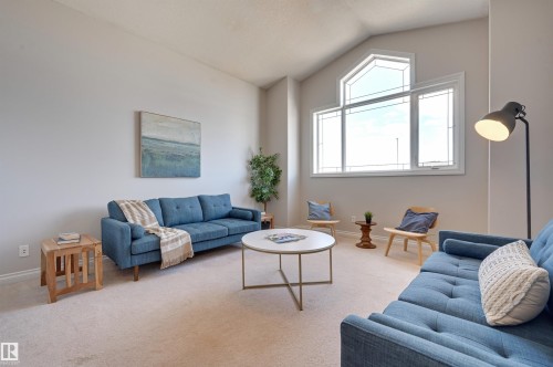 Living area featuring vaulted ceilings, large windows providing natural light, and carpeted flooring - 24 Birchmont Drive, Leduc, AB - Indoor Photo Showing Living Room