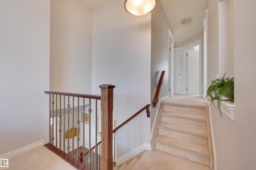 The property features a staircase with carpeted steps and a wooden handrail with decorative metal balusters - 24 Birchmont Drive, Leduc, AB - Indoor Photo Showing Other Room
