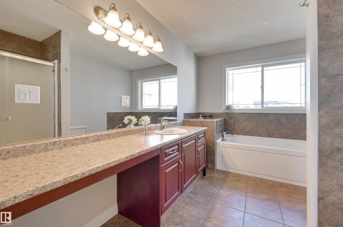 This bathroom features a spacious vanity with a light-colored countertop, a built-in bathtub, and a shower with a clear glass enclosure - 24 Birchmont Drive, Leduc, AB - Indoor Photo Showing Bathroom