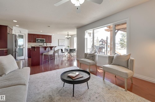 The open concept living area features hardwood floors, a ceiling fan, and a large window overlooking the exterior - 24 Birchmont Drive, Leduc, AB - Indoor Photo Showing Living Room