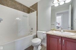 This bathroom features a bathtub with a shower, a toilet, and a vanity with a sink - 