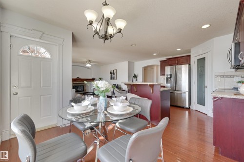 The property features hardwood floors, a kitchen with stainless steel appliances, and a central chandelier - 24 Birchmont Drive, Leduc, AB - Indoor Photo Showing Dining Room