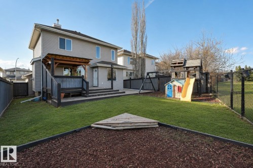 Expansive backyard featuring a manicured lawn, multi-level composite deck with built-in seating, and a wood pergola - 24 Birchmont Drive, Leduc, AB - Outdoor