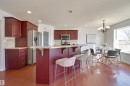 The kitchen features dark wood cabinetry, stainless steel appliances, and a breakfast bar with a light-colored countertop - 24 Birchmont Drive, Leduc, AB  - Indoor Photo Showing Kitchen 