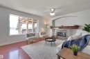 The living room features hardwood flooring, a large window providing ample natural light, and a fireplace with a tiled surround and a wooden mantel - 24 Birchmont Drive, Leduc, AB  - Indoor Photo Showing Living Room With Fireplace 
