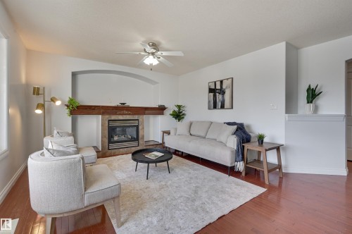Living area featuring hardwood flooring, a gas fireplace with a wood mantle, and a ceiling fan - 24 Birchmont Drive, Leduc, AB - Indoor Photo Showing Living Room With Fireplace