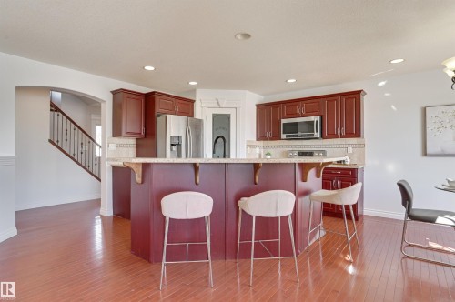 Kitchen with cherry wood cabinetry, stainless steel appliances, and a breakfast bar with seating - 24 Birchmont Drive, Leduc, AB - Indoor Photo Showing Kitchen