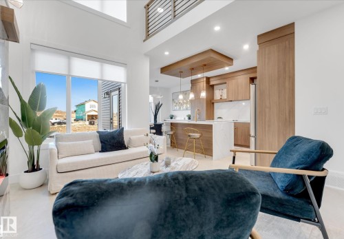 Open-concept living area featuring a two-story ceiling, large windows with roller shades, and light-toned tile flooring - 4727 17 Avenue Sw, Edmonton, AB - Indoor Photo Showing Living Room