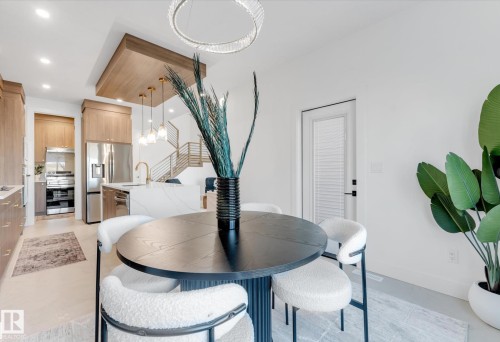 Open-concept living space featuring a modern kitchen with light wood cabinetry, stainless steel appliances, and a waterfall-edge island - 4727 17 Avenue Sw, Edmonton, AB - Indoor Photo Showing Dining Room