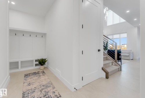 Entryway featuring light-toned flooring and a built-in mudroom bench with coat hooks - 4727 17 Avenue Sw, Edmonton, AB - Indoor Photo Showing Other Room