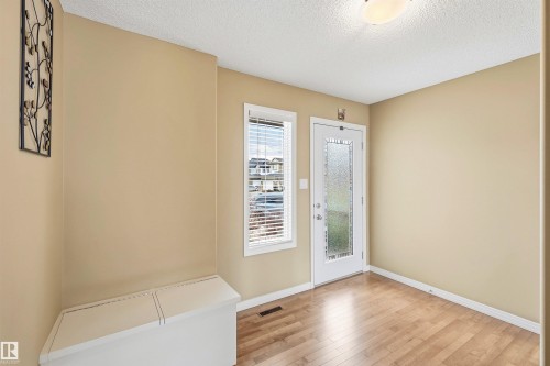 Entryway featuring wood-finish flooring, a full-lite exterior door with privacy glass, a single window with blinds, and a flush-mount ceiling light fixture - 2340 Hagen Link, Edmonton, AB - Indoor Photo Showing Other Room