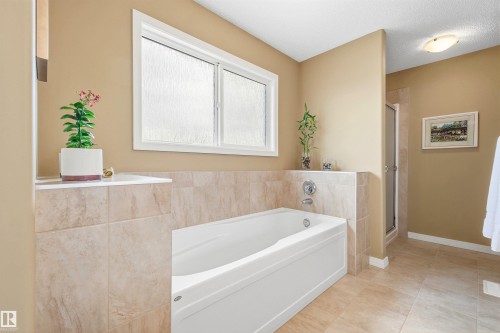 Soaking tub with tile surround and chrome fixtures - 2340 Hagen Link, Edmonton, AB - Indoor Photo Showing Bathroom