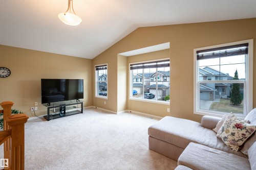 Spacious room featuring vaulted ceilings, light-toned carpeting, and a prominent bay window - 2340 Hagen Link, Edmonton, AB - Indoor Photo Showing Living Room