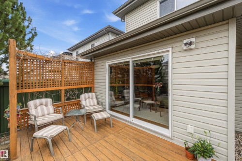 Outdoor wood-finish deck featuring a lattice privacy screen and sliding glass patio doors, set against a light-colored siding exterior - 2340 Hagen Link, Edmonton, AB - Outdoor With Deck Patio Veranda With Exterior