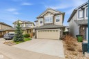 Two-story residence featuring a neutral siding exterior with stone accents, a dual garage door, and a prominent front-facing bay window - 2340 Hagen Link, Edmonton, AB  - Outdoor With Facade 