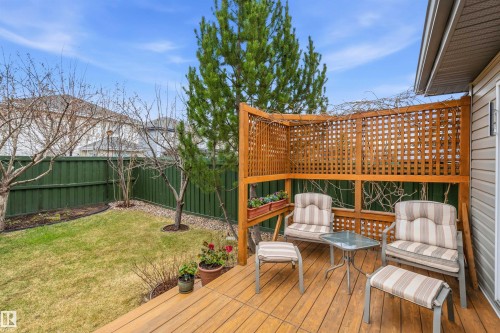 Expansive wooden deck featuring a built-in lattice privacy screen and direct access to a green-fenced yard with mature trees and landscaping - 2340 Hagen Link, Edmonton, AB - Outdoor With Deck Patio Veranda With Exterior