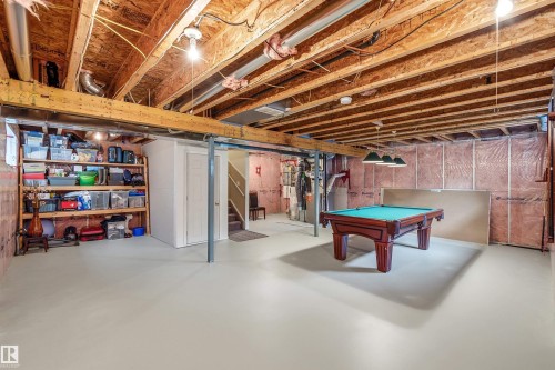 Expansive unfinished basement featuring exposed wood joists, a painted concrete floor, and insulated perimeter walls - 2340 Hagen Link, Edmonton, AB - Indoor Photo Showing Basement