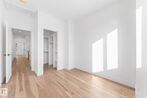 This room features hardwood floors, white walls, and a built-in closet with shelving and a hanging rod - 11021 132 Street, Edmonton, AB - Indoor Photo Showing Other Room