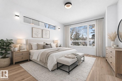 This room features light-colored hardwood flooring, a large window providing ample natural light, and a white ceiling with a contemporary flush-mount light fixture - 11021 132 Street, Edmonton, AB - Indoor Photo Showing Bedroom