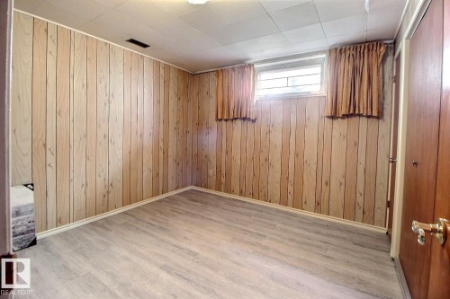 Room with wood-finish paneling, light wood-finish flooring, a drop ceiling, and two windows with security bars - 9512 134 Avenue, Edmonton, AB - Indoor Photo Showing Other Room