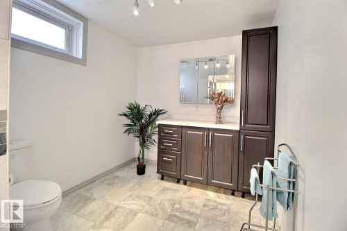 Bathroom featuring a wide vanity with dark wood-finish cabinetry, a white countertop, and a mirrored medicine cabinet with track lighting - 9512 134 Avenue, Edmonton, AB - Indoor Photo Showing Bathroom