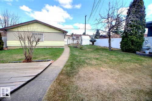 Expansive backyard featuring a concrete pathway, a wooden deck area, and a white privacy fence - 9512 134 Avenue, Edmonton, AB - Outdoor