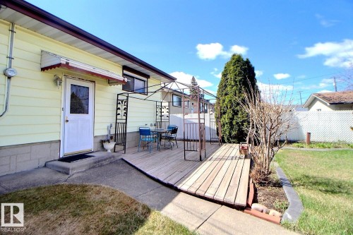 Rear exterior featuring a wooden deck with an attached metal pergola, a concrete patio, and a side door with a protective awning - 9512 134 Avenue, Edmonton, AB - Outdoor With Exterior