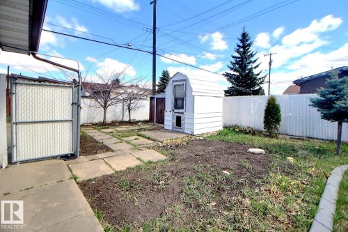 Backyard featuring a white chain-link fence, mature trees, and a storage shed - 9512 134 Avenue, Edmonton, AB - Outdoor