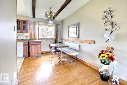 Bright dining area featuring wood-finish flooring, exposed ceiling beams, a built-in bench, and a large window - 9512 134 Avenue, Edmonton, AB - Indoor Photo Showing Dining Room