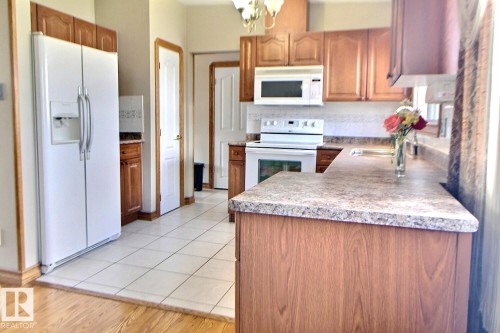 Kitchen featuring wood-finish cabinetry, white tile flooring, and speckled countertops - 9512 134 Avenue, Edmonton, AB - Indoor Photo Showing Kitchen