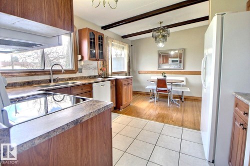 Kitchen featuring wood-finish cabinetry, a double basin stainless steel sink, a built-in dishwasher, and an electric cooktop - 9512 134 Avenue, Edmonton, AB - Indoor Photo Showing Kitchen With Double Sink