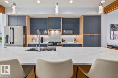 Kitchen featuring a large central island with an integrated sink, white countertop, and contemporary pendant lighting - 11245 64 Street, Edmonton, AB - Indoor Photo Showing Kitchen With Upgraded Kitchen