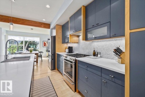 Modern kitchen featuring light wood-finish flooring, white countertops, and a hexagonal tile backsplash - 11245 64 Street, Edmonton, AB - Indoor Photo Showing Kitchen With Upgraded Kitchen