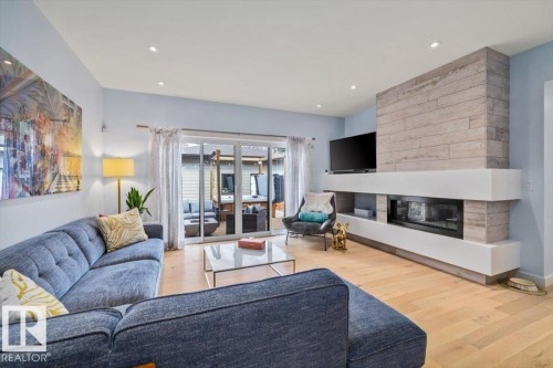 Living area featuring wood-finish flooring, recessed lighting, and a modern fireplace with a tiled surround - 11245 64 Street, Edmonton, AB - Indoor Photo Showing Living Room With Fireplace