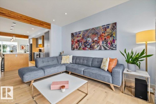 Open-concept living area featuring light wood-finish flooring, recessed lighting, and a prominent wood beam detail - 11245 64 Street, Edmonton, AB - Indoor Photo Showing Living Room