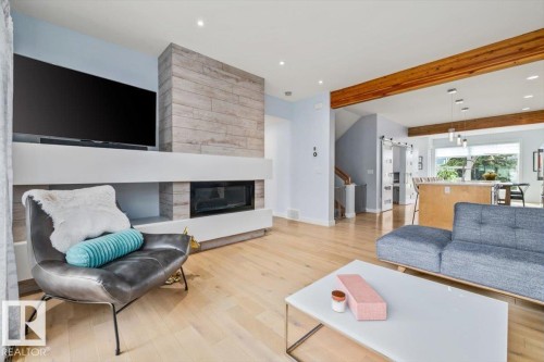 Living area featuring a floor-to-ceiling fireplace with a textured wood-finish surround, a linear electric fireplace insert, and built-in shelving - 11245 64 Street, Edmonton, AB - Indoor Photo Showing Living Room With Fireplace