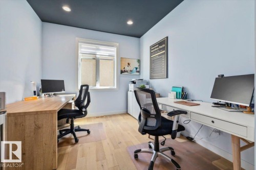 Dedicated workspace featuring light wood-finish flooring, a window with roller blinds, recessed ceiling lighting, and a dark contrasting ceiling - 11245 64 Street, Edmonton, AB - Indoor Photo Showing Office