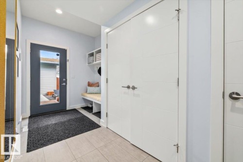Entryway featuring light-toned tile flooring, a built-in bench with open storage, and white built-in shelving - 11245 64 Street, Edmonton, AB - Indoor Photo Showing Other Room