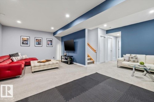 Carpeted lower level featuring recessed lighting, a painted accent wall, and a carpeted staircase with wood handrails - 11245 64 Street, Edmonton, AB - Indoor