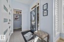 Entryway featuring light gray tile flooring, a modern glass-paneled entry door, white interior doors with frosted glass inserts, and a powder room with a transom window - 11245 64 Street, Edmonton, AB  - Indoor Photo Showing Other Room 