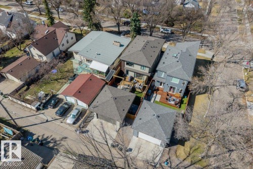 Aerial view showcasing multiple residential properties, featuring a grey-sided home with a dark-grey shingle roof, rear deck, and a fenced yard with artificial turf - 11245 64 Street, Edmonton, AB - Outdoor With View