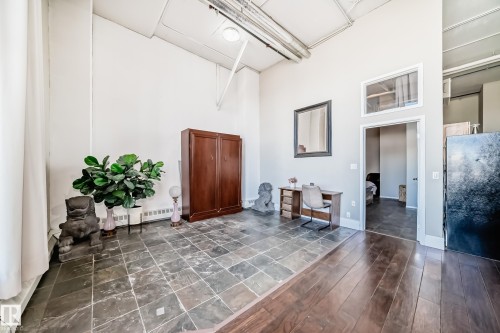 Versatile interior space featuring high ceilings, exposed ductwork, and a combination of stone tile and wood-finish flooring - 1003 10179 105 Street Nw, Edmonton, AB - Indoor Photo Showing Other Room