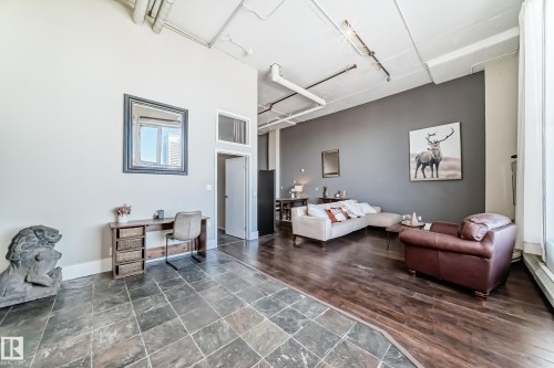 Spacious interior featuring a combination of stone tile flooring and wood-finish flooring, a neutral color palette, exposed ceiling ductwork, and a partial accent wall - 1003 10179 105 Street Nw, Edmonton, AB - Indoor