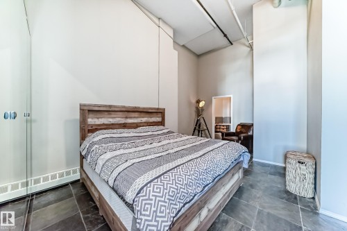 Open room featuring dark slate tile flooring and exposed industrial-style ceiling elements - 1003 10179 105 Street Nw, Edmonton, AB - Indoor Photo Showing Bedroom
