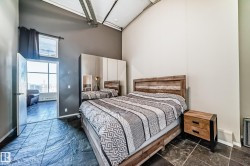 Bedroom featuring textured tile flooring and high ceilings with exposed ductwork - 